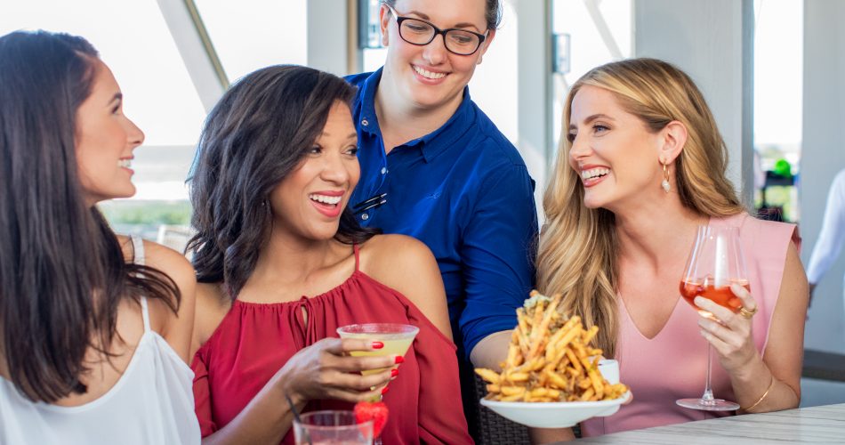 A group of women enjoying food and drinks at Fish Out of WaterColor Restaurant in South Walton, Florida